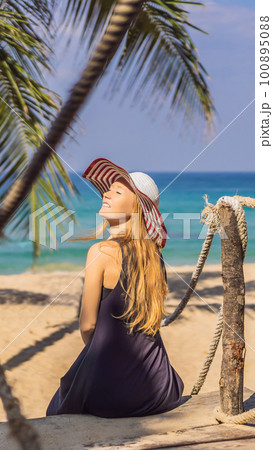 Vacation on tropical island. Woman in hat enjoying sea view from wooden bridge 100895088