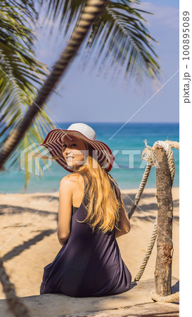 Vacation on tropical island. Woman in hat enjoying sea view from wooden bridge 100895089