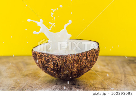 Coconut fruit and milk splash inside it on yellow background Coconut fruit and milk splash inside it on yellow background 100895098