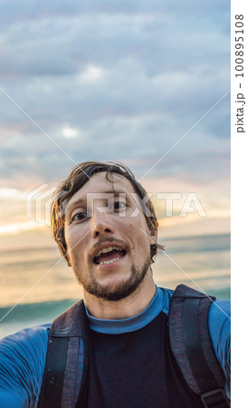A man takes a selfie on the background of the sea and sunset 100895108