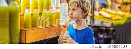 Boy drinking sugar cane juice on the Asian market Boy drinking sugar cane juice on the Asian market 100895183