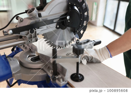 Professional carpenter controls process of sawing laminate Professional carpenter controls process of sawing laminate 100895608