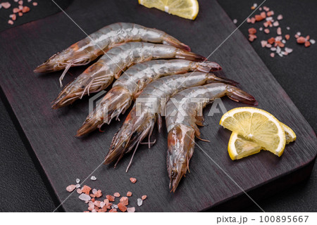 Tiger prawn or langoustine raw with spices and salt on a wooden cutting board 100895667