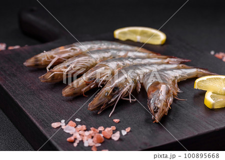 Tiger prawn or langoustine raw with spices and salt on a wooden cutting board 100895668