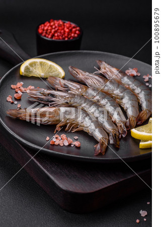 Tiger prawn or langoustine raw with spices and salt on a wooden cutting board 100895679