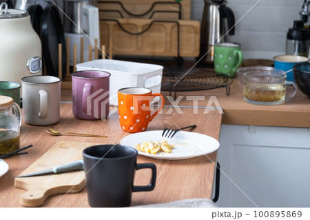 A mess in the kitchen, dirty dishes on the table, scattered things, unsanitary conditions. The dishwasher is full, the kitchen is untidy, everyday life 100895869