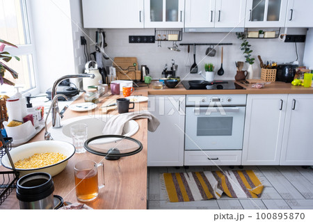 A mess in the kitchen, dirty dishes on the table, scattered things, unsanitary conditions. The dishwasher is full, the kitchen is untidy, everyday life 100895870