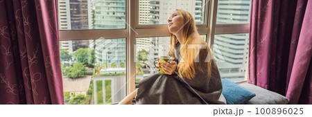 Woman wrapped in a blanket and looking at the big city BANNER, LONG FORMAT 100896025