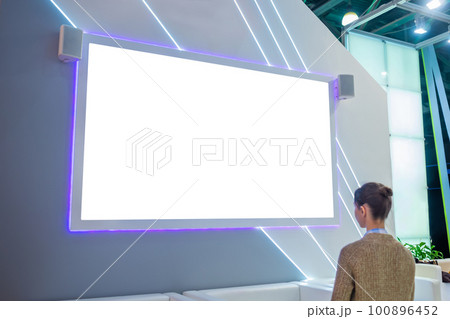 Woman looking at empty white large wall display at trade show - mockup image 100896452