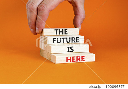 The future is here symbol. Concept words The future is here on wooden block. Beautiful orange table orange background. Businessman hand. Motivational business the future is here concept. Copy space. 100896875