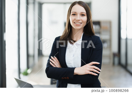 Portrait of a woman business owner showing a happy smiling face as he has successfully invested her business using computers and financial budget documents at work. 100898266