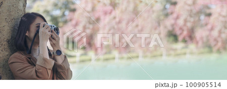 Banner Asian Women with vintage film camera take a photo. Panorama female photographer look at photo from professional camera outdoor. Young woman shooting photo in green nature park with copy space Banner Asian Women with vintage film camera take a photo. Panorama female photographer look at photo from professional camera outdoor. Young woman shooting photo in green nature park with copy space 100905514