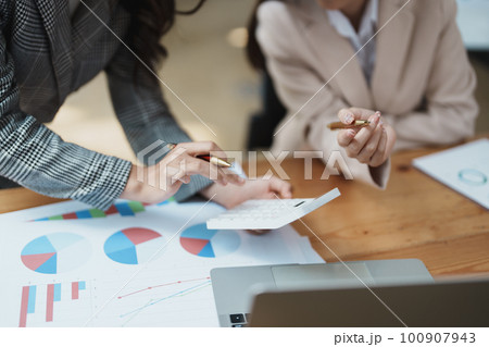 Financial analysts analyzing business reports on planned investment projects during corporate meeting discussions showcase successful teamwork with marketing plan, computers and calculators to work. 100907943