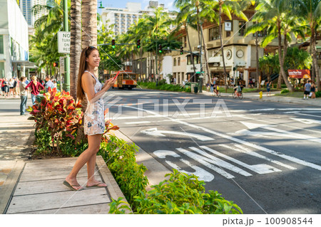 Waikiki tourist woman walking in Honolulu city street using mobile phone. Hawaii Summer vacation destination Waikiki tourist woman walking in Honolulu city street using mobile phone. Hawaii Summer vacation destination 100908544