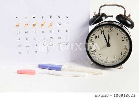 Positive inkjet pregnancy test, black retro alarm clock and white calendar with dates of the last menstruation marked. Women's health, ovulation, fertility, pregnancy planning and motherhood. Ad space Positive inkjet pregnancy test, black retro alarm clock and white calendar with dates of the last menstruation marked. Women's health, ovulation, fertility, pregnancy planning and motherhood. Ad space 100913623