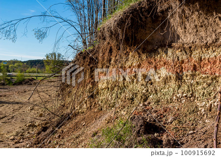 Section of a part of a slope with layers of variegated clay covered with a layer of soil on top Section of a part of a slope with layers of variegated clay covered with a layer of soil on top 100915692