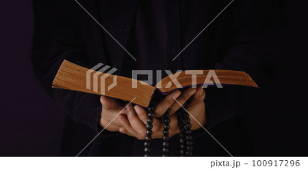 Spirituality, Religion and Hope Concept. Person Praying by Holy Bible and Bead. Symbol of Humility, Supplication, Believe and Faith for Christian People. Dark Tone. Cropped and Selective focus 100917296