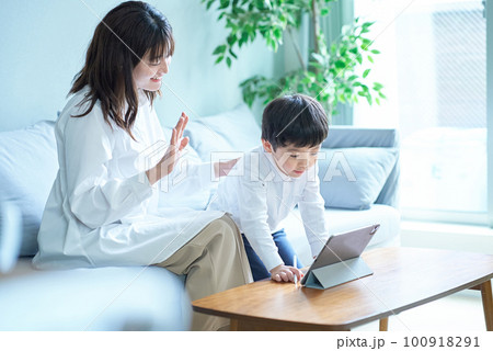 ソファに座ってタブレットPCの画面を見る親子 ソファに座ってタブレットPCの画面を見る親子 100918291