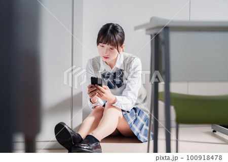 スマホを見ながら落ち込む女子高生 スマホを見ながら落ち込む女子高生 100918478