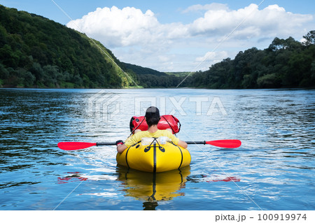 Tourist on yellow packraft boat on sunrise Dnister river Tourist on yellow packraft boat on sunrise Dnister river 100919974