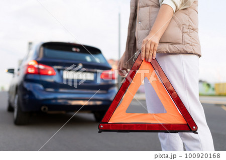 a woman driver puts a triangular road sign due to a car breakdown on the road a woman driver puts a triangular road sign due to a car breakdown on the road 100920168