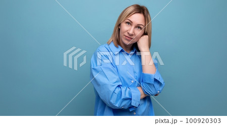 portrait of a confident calm european blond woman in a shirt on a blue background with copyspace portrait of a confident calm european blond woman in a shirt on a blue background with copyspace 100920303