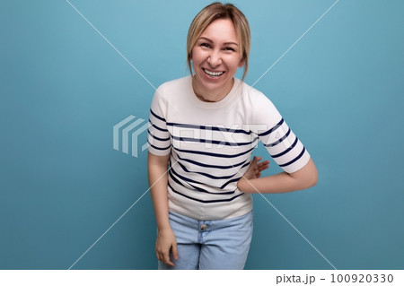 bright photo of a positive joyful happy blonde girl in a striped sweater on a blue background with 100920330