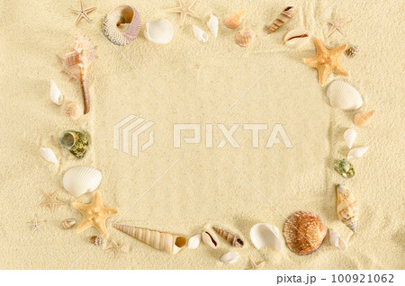 Frame made of seashells and starfishes on a sand background. Marine summer concept. Copy space between seashells and starfishes arranged in a square. 100921062