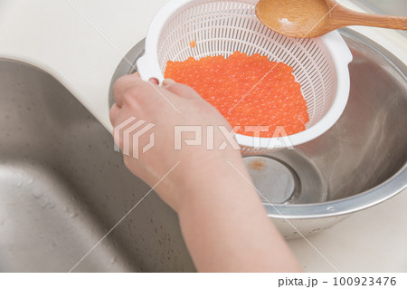 【イクラの醤油漬けを作るために、洗い終わった生イクラをスプーンでお酒を馴染ませる】 【イクラの醤油漬けを作るために、洗い終わった生イクラをスプーンでお酒を馴染ませる】 100923476