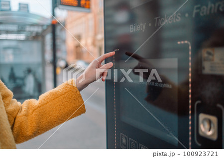 Woman hand using self service machine in transfer area, doing self check in or buying plane tickets at automated machine with touchscreen interactive display in modern airport terminal building 100923721