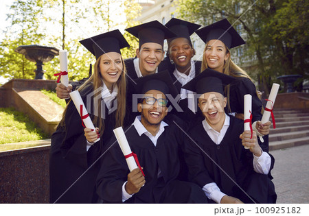Group portrait of happy excited graduates in academic gowns and caps holding diploma scrolls. Group portrait of happy excited graduates in academic gowns and caps holding diploma scrolls. 100925182