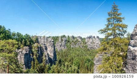 Panoramic view over monumental Bastei sandstone pillars and ancient bridge near Kurort Rathen village in the national park Saxon Switzerland by Dresden and Czechish border, Saxony, Germany. Panoramic view over monumental Bastei sandstone pillars and ancient bridge near Kurort Rathen village in the national park Saxon Switzerland by Dresden and Czechish border, Saxony, Germany. 100926159