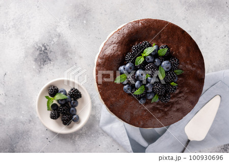 Fresh delicious homemade chocolate cake decorated with blackberries, blueberries and mint. Ready for eating. top view. place for text. Gray background 100930696