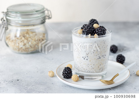 overnight oats with coconut milk, chia seeds, hazelnuts and blackberries on a gray background. healthy diet breakfast. copy space. horizontal image 100930698