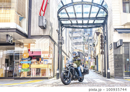 大型アメリカンバイクに乗って横浜元町ショッピングストリートに買い物に来た女性ライダー 100935744