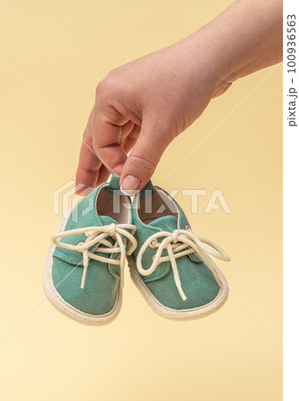 Female hand holding tiny baby shoes. Newborn concept. Female hand holding tiny baby shoes. Newborn concept. 100936563