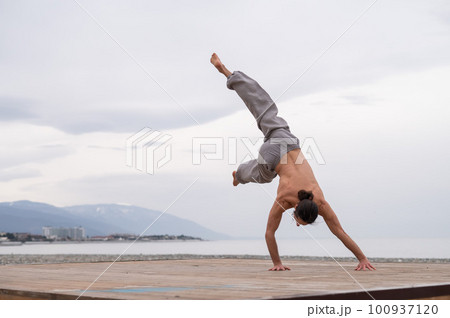 Shirtless caucasian man doing acrobatic wheel on the beach. Shirtless caucasian man doing acrobatic wheel on the beach. 100937120