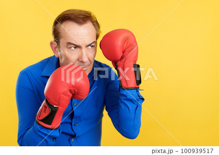 An angry mature man with boxing gloves 100939517