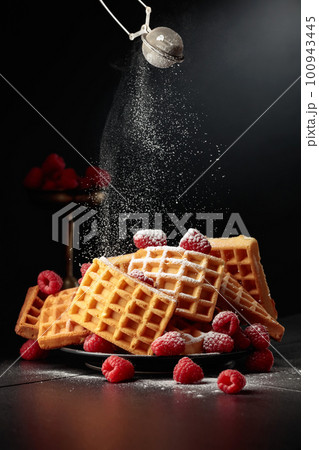 Belgian waffles with raspberries sprinkled with powdered sugar. Belgian waffles with raspberries sprinkled with powdered sugar. 100943445