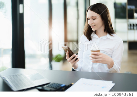 Portrait of a business woman talking on the phone and drinking coffee. 100943561