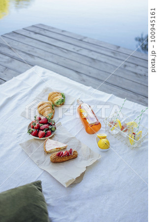 Bottle of strawberry and lemon smoothie, soda glasses with straws, herb croissants, sweet cakes and fresh strawberries 100945161
