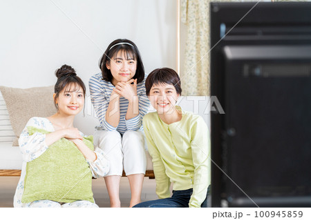 リビングでテレビを友達と見る若い女性 100945859