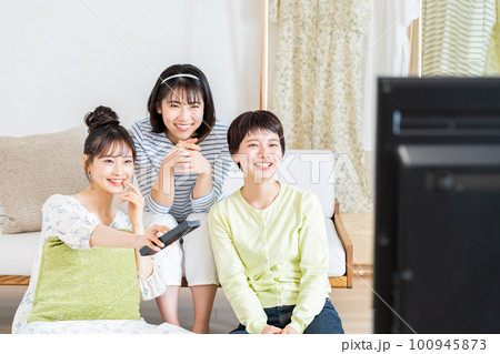 リビングでテレビを友達と見る若い女性 100945873