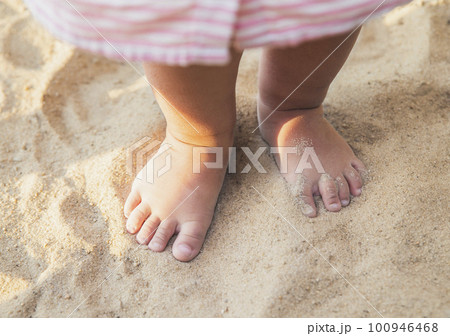 little baby feet of a child who walks along the seashore 100946468