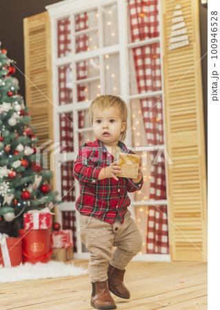 baby in trousers and a plaid shirt plays on the floor with wooden cube baby in trousers and a plaid shirt plays on the floor with wooden cube 100946528
