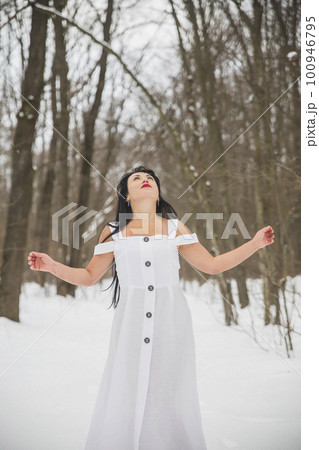 Attractive woman in white dress praying in the winter forest Attractive woman in white dress praying in the winter forest 100946795