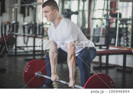 athlete doing deadlift n style sumo in gym 100946894
