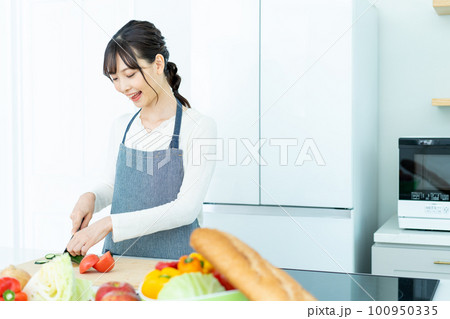 キッチンで料理をするエプロンの若い女性 100950335