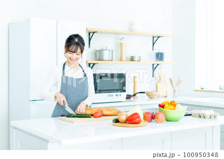 キッチンで料理をするエプロンの若い女性 100950348