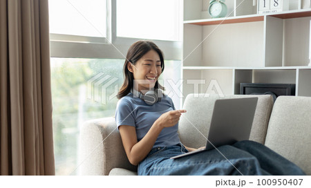 Young Asian woman greets his friends and teachers in a live video with a smile on his face, Online communication , Stay home, New normal, VDO Call, Social distancing, Internet learning. 100950407